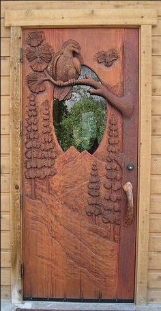 a wooden door with a carved tree and bird on it's side, in front of a house