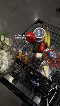 a shopping cart filled with lots of different types of food and flowers on top of it