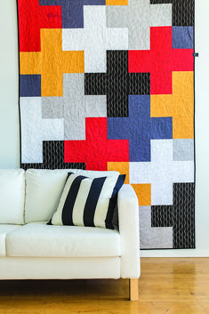 a white couch sitting in front of a colorful quilt