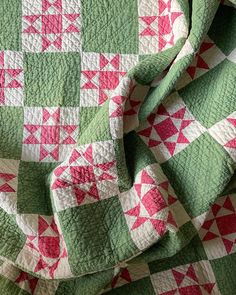 a green and pink quilt on top of a bed