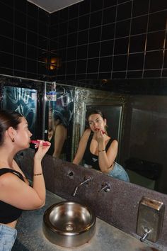 a woman brushing her teeth in front of a mirror