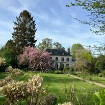 a large white house sitting in the middle of a lush green field with lots of trees