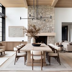 a dining room table with chairs and a vase on top of it in front of a fireplace