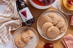 some cookies are sitting on plates next to a bottle of tea and a bowl of honey