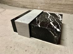 a black and white marble block sitting on top of a cement floor next to a wall