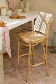 a white counter top sitting next to a bar stool with a basket on the back