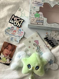 a green stuffed animal laying on top of a bed next to pictures and stickers