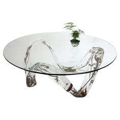 a glass table with a plant on top and legs in the shape of an x