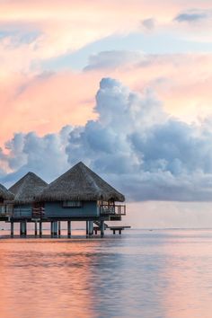 an image of a pier in the middle of water with clouds and sky above it