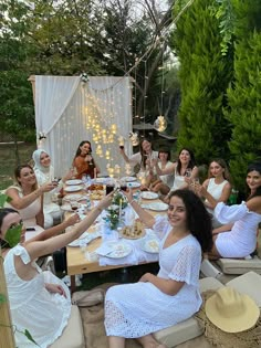 a group of women sitting around a table with food and drinks in front of them