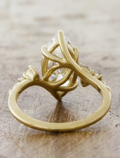 a close up of a gold ring on a wooden table with a diamond in the center