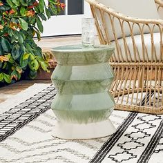 a wicker chair sitting on top of a rug next to a table with a vase