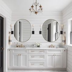 a white bathroom with two mirrors and double sinks