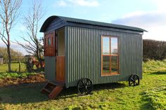 a small green house sitting on top of a lush green field next to a horse