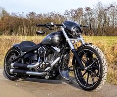 a black motorcycle is parked on the side of the road in front of some tall grass