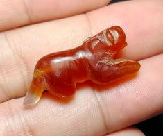 a small glass animal sitting on top of someone's finger