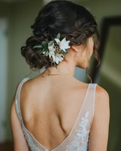 the back of a woman's head with flowers in her hair, wearing a wedding dress