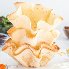 a bowl that has some kind of food inside of it on a table next to bowls and utensils