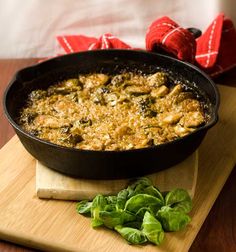 a skillet filled with food sitting on top of a wooden table next to red napkins