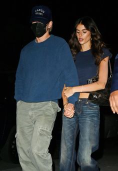 a man and woman walking together in the dark with a face mask covering their faces