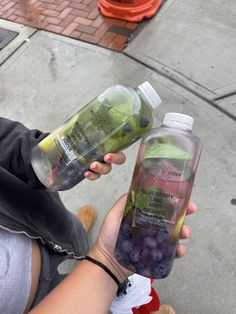 a woman holding two bottles of water and grapes