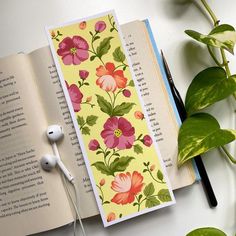 an open book with flowers on it next to headphones