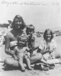 an old black and white photo of people on the beach with one holding a child