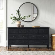 a black dresser with a round mirror above it