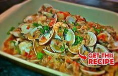 a bowl filled with clams and vegetables on top of a table