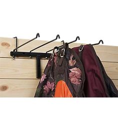 the coat rack has two coats hanging from it's hooks and is next to a wooden wall