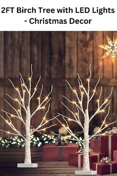 three white christmas trees with lights and presents in front of them on a wooden table