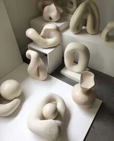 several white sculptures are on display in a room with concrete steps and flooring that have been made to look like interlocked shapes