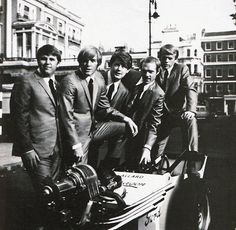 men in suits and ties are posing with an engine on the back of a car