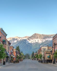 an empty city street with mountains in the backgrouds and snow on the tops