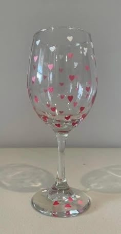 a wine glass with hearts painted on the bottom and inside is sitting on a table