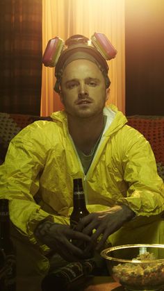 a man sitting on a couch with a beer in his hand and wearing yellow raincoats