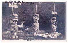 three totems standing in front of trees and signs on poles, one holding a sign