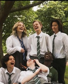 a group of young people standing next to each other in front of trees and grass