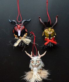 three masks hanging from strings on a black surface