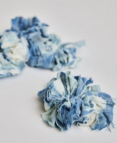 two pieces of blue and white fabric with frayed edges on a white surface,