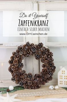 a wreath made out of pine cones sitting on top of a table next to christmas decorations