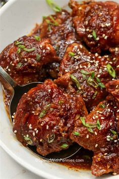 a white bowl filled with meat covered in sauce and garnished with green herbs