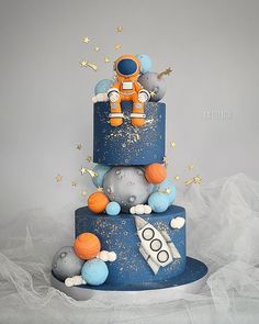 a three tiered space themed cake with an astronaut on top