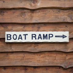 a boat ramp sign mounted to the side of a wooden building with an arrow pointing in opposite directions