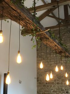 several light bulbs hanging from the ceiling in a room with exposed beams and stone walls