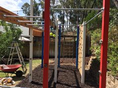 an outdoor play area with swings, climbing bars and balls in the ground next to a wheelbarrow