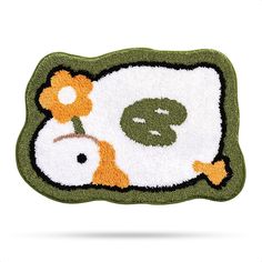 a green and white rug with an orange flower on the front, and a peace sign in the middle