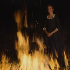 a woman standing in front of a fire