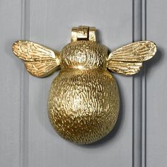 a gold bee door knocker on a white door