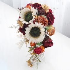 a bridal bouquet with sunflowers and roses on a white tablecloth background